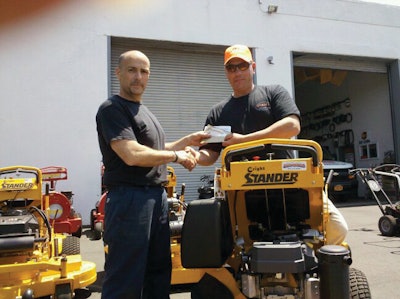 Artie D'Ambra (left) presents a $500 AMEX gift check to customer Peter Guido of PKG Gardens for the 500th Wright mower sold.