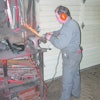 Dealership technician sharpening lawnmower blades with a powered handheld grinder. Some still prefer this method.