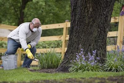 16076 a man spreading fertilizer on his garden pv 5aabcd5200561