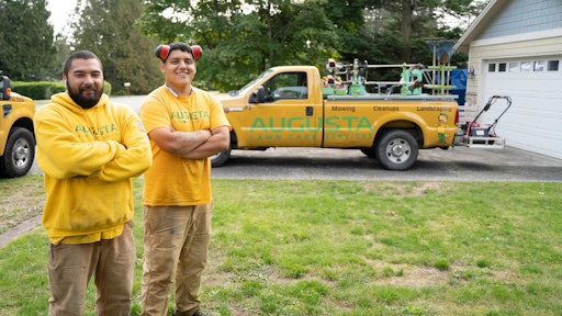 Members of the Augusta Lawn Care Services crew in uniform, in front of branded truck.