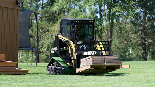 A small sit-in compact track loader moves a loaded pallet across a lawn. Small residential or backyard projects don’t necessarily need a huge machine.