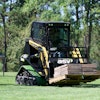 A small sit-in compact track loader moves a loaded pallet across a lawn. Small residential or backyard projects don’t necessarily need a huge machine.