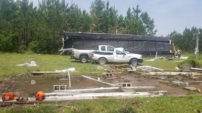 A home, ripped from a concrete foundation by high winds, damaged two trucks and blew into a row of pine trees where it eventually stopped. Fortunately, there were no fatalities as a father and his young child crawled out of the debris from a small hole in the end of the home.