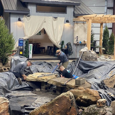 Brian Helfrich and Chris Hanson of TEAM Aquascape set a stone slab bridge for Atlantis Water Gardens’ display.
