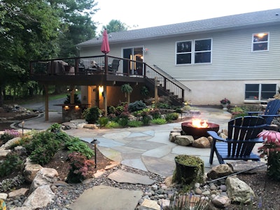 Backyard decking and a landscape with a central fire pit create a relaxing hangout.