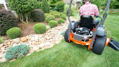 A mower operator practicing safe power equipment guidelines while he works.