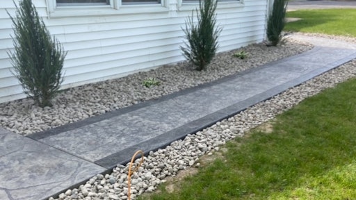 Archbold Landscaping laid natural stones around a recently installed walkway.