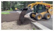 A skid steer laying dirt to prepare the area for sod.