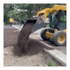 A skid steer laying dirt to prepare the area for sod.