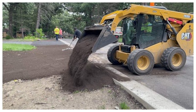 A skid steer laying dirt to prepare the area for sod.