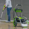 Greenworks electric pressure washer cleaning concrete floor with green and gray equipment