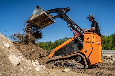 Construction skid-steer loader moving earth on a rocky work site