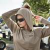 Worker in beige Milwaukee hoodie adjusting hood, standing near construction equipment