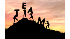 Silhouettes of people forming the word TEAM on a hillside at sunset