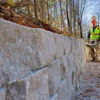 Construction worker in safety vest installing concrete retaining wall on hillside property