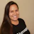 Smiling woman with long dark hair wearing a black Lumaapp branded t-shirt against a neutral beige background Headshot