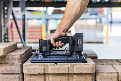 Worker using a compact power drill on brick surface in construction warehouse setting