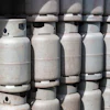Multiple white propane cylinders stacked in rows with valve caps visible on top