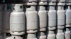 Multiple white propane cylinders stacked in rows with valve caps visible on top