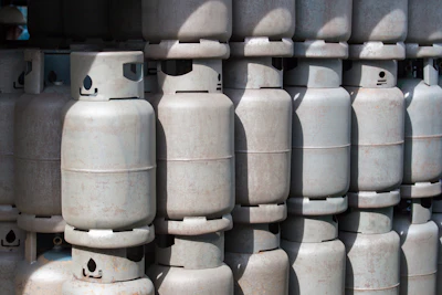 Multiple white propane cylinders stacked in rows with valve caps visible on top