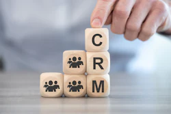 Hand placing wooden block with letter C on stacked blocks spelling CRM with people icons