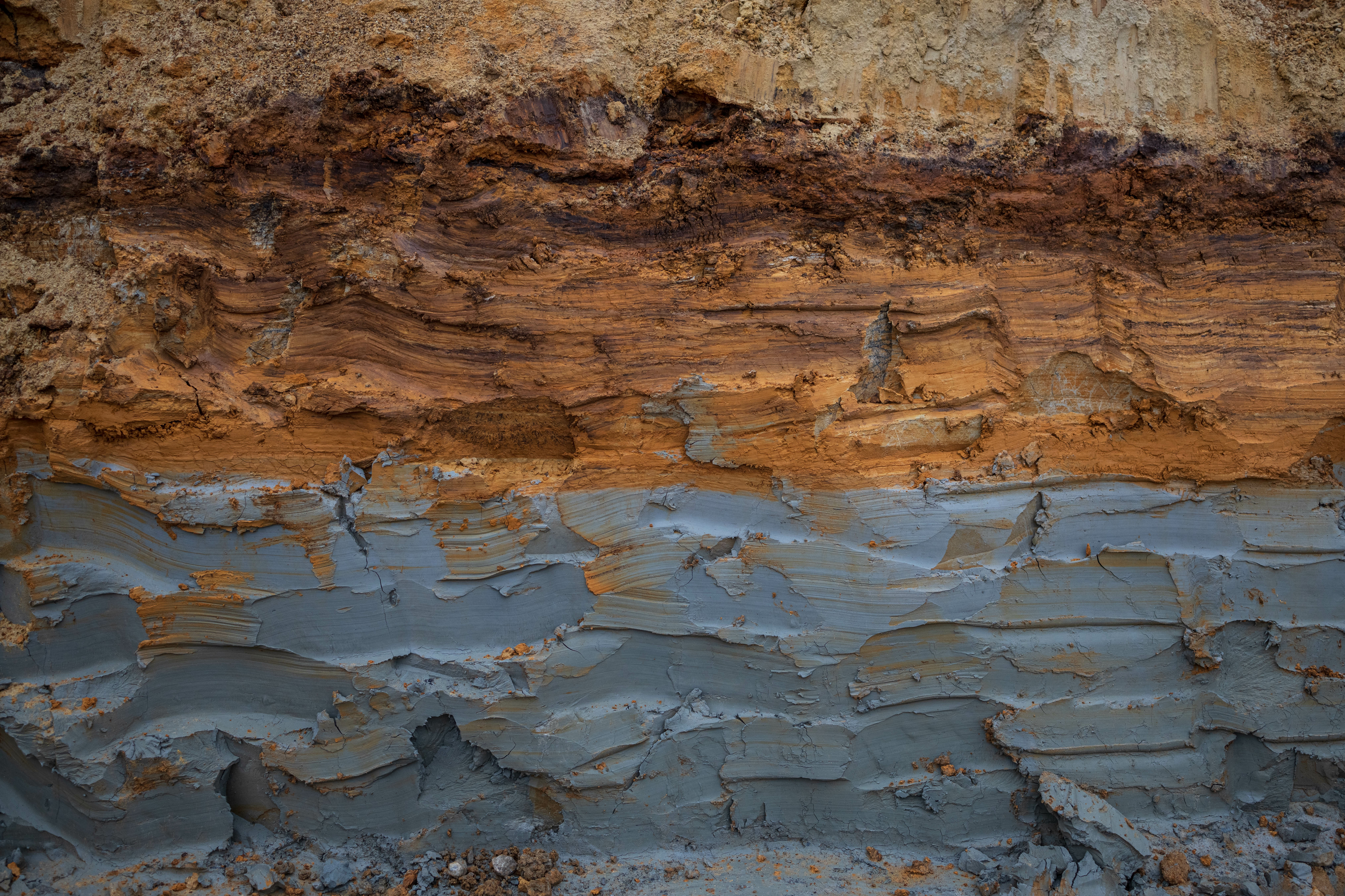 Stratified rock formation showing layered sedimentary deposits with rust-colored oxidation and weathered surfaces