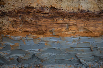 Stratified rock formation showing layered sedimentary deposits with rust-colored oxidation and weathered surfaces