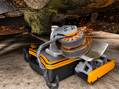 Industrial floor sander with orange and black striping on weathered concrete surface under rusty metal framework