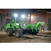 Bright green wheeled loader with articulated bucket attachment on construction site at night