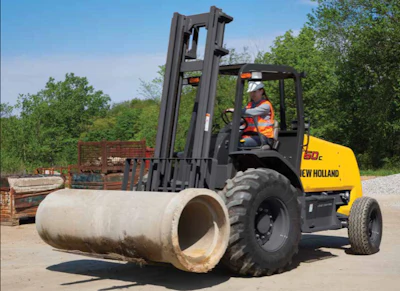 New Holland forklift operator lifting concrete pipe in outdoor industrial yard with trees and equipment in background