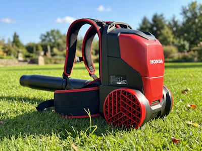 Honda red and black backpack leaf blower with padded straps on green grass outdoors