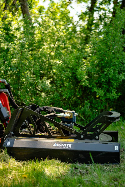 IGNITE wood chipper with black frame positioned in grass against lush green hedge backdrop