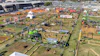 Aerial view of large agricultural equipment exhibition with machinery displays, vendor tents, and crowds at outdoor fairground.