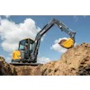 Yellow and black John Deere excavator digging earth at a construction site under blue sky