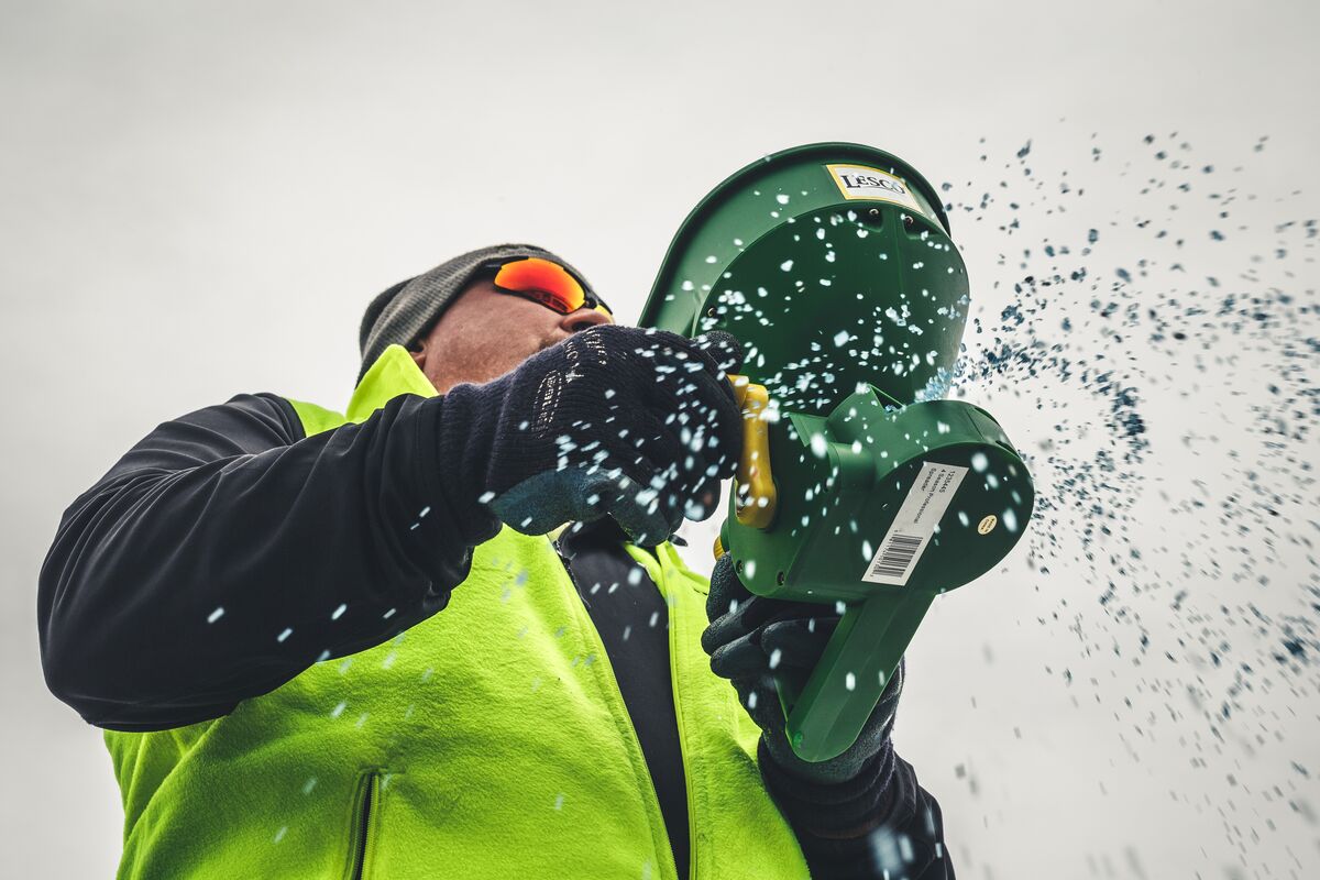Worker in safety gear holding green buckets with water splashing against white background