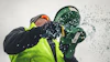 Worker in safety gear holding green buckets with water splashing against white background