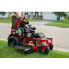 Red and black Toro zero-turn radius mower on residential driveway with operator