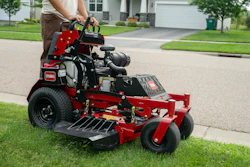 Red and black Toro zero-turn radius mower on residential driveway with operator
