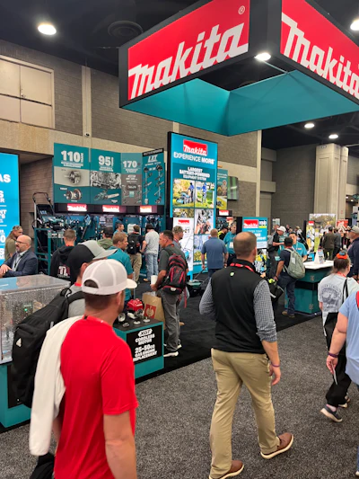 Makita booth at trade show with red and teal signage, crowds of visitors exploring power tools and equipment displays