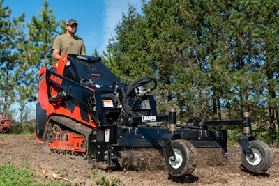 Operator using red and black Chauvin wood chipper with trailer attachment in forested outdoor setting