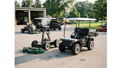 Landscaping equipment including zero-turn mowers and utility vehicles displayed in a commercial yard with storage building