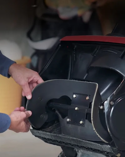 Person opening black fuel door panel on red vehicle showing interior fasteners