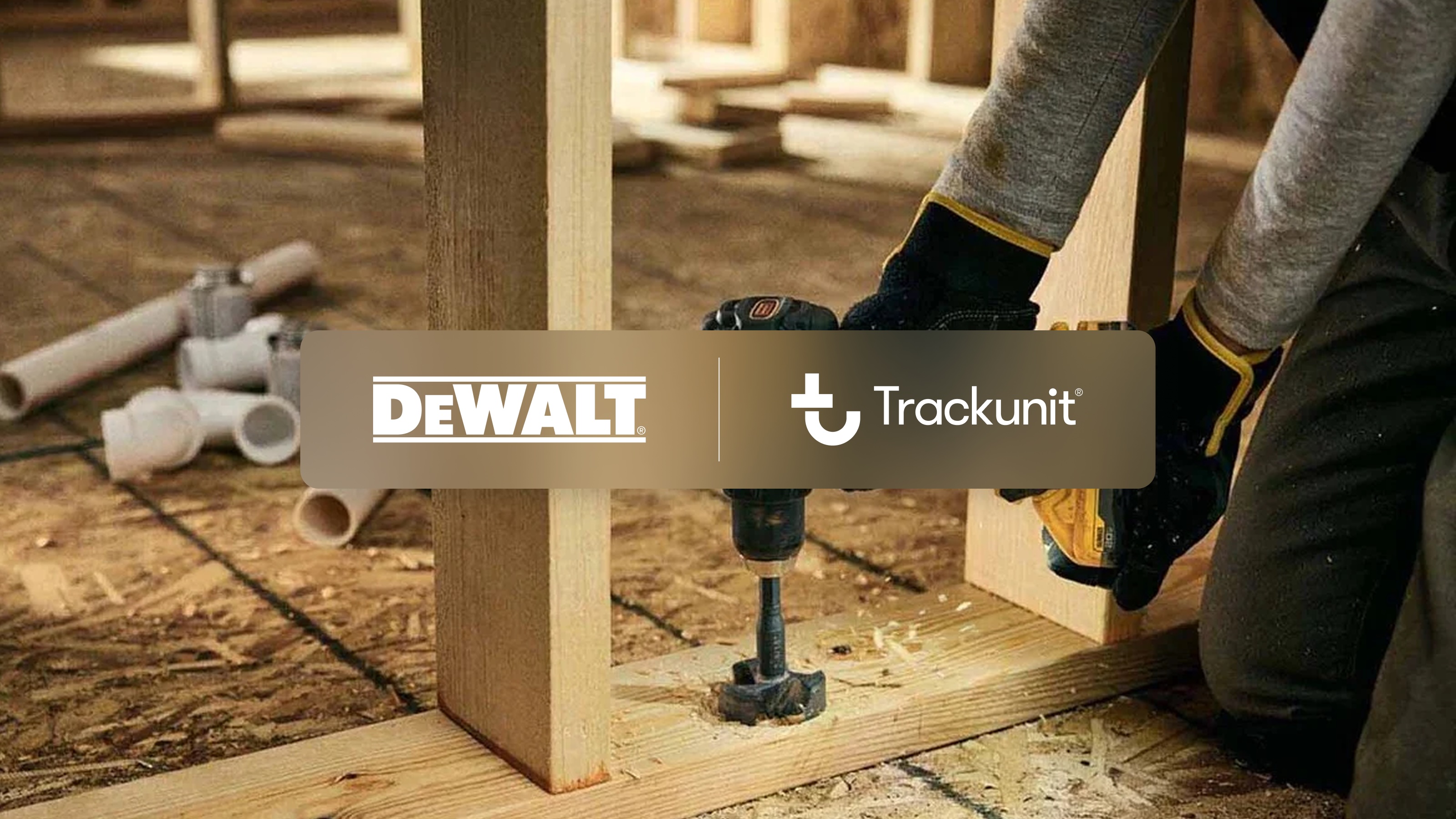 DeWalt and Trackunit logos displayed over woodworking scene with power drill on wooden frame