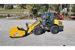 Yellow New Holland wheel loader with Arctic snow pusher attachment parked at equipment yard