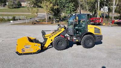 Yellow New Holland wheel loader with Arctic snow pusher attachment parked at equipment yard
